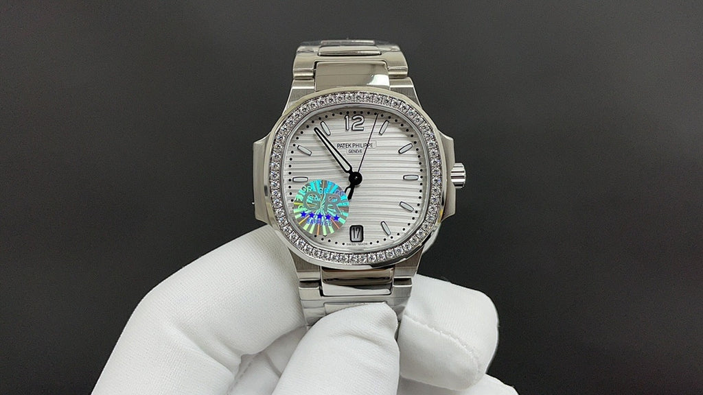 Silver metal wristwatch on a white-gloved hand, white dial and rainbow center motif
