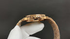 Gold-tone wristwatch open caseback showing mechanical movement and crown