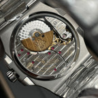 Patek Philippe watch case back with visible gears, gold bridge, and screw heads