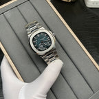 Stainless steel Patek Philippe watch with dark dial, teal accents, and metal bracelet