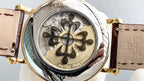 Patek Philippe watch caseback close-up with engraved floral pattern and brown leather strap