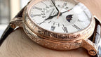 Patek Philippe watch close-up with white dial and ornate gold-tone case, visible crown