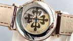 Gold wristwatch with brown leather strap, open dial detail with patterned rotor
