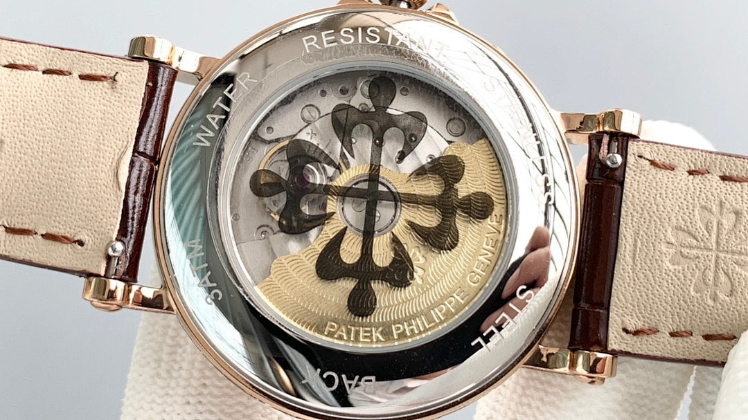 Gold wristwatch with brown leather strap, open dial detail with patterned rotor
