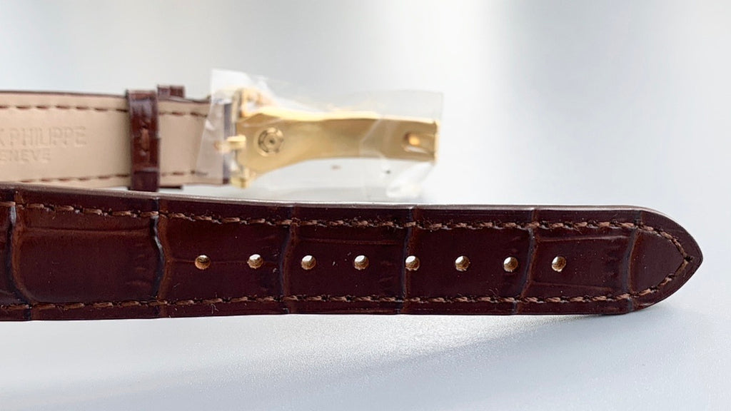 Brown leather watch strap with gold buckle and row of metal rivets