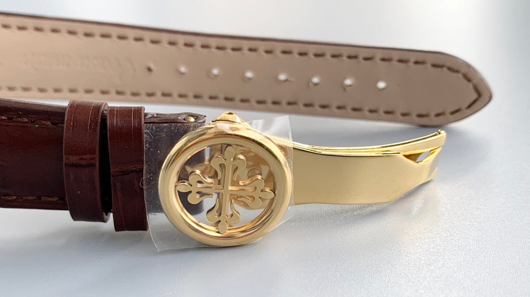 Brown leather strap with round gold clasp and engraved center medallion