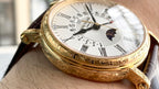 Gold wristwatch on wrist, white dial with Roman numerals and moonphase