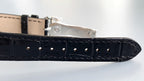 Black leather watch strap with metal buckle and rows of stitch holes