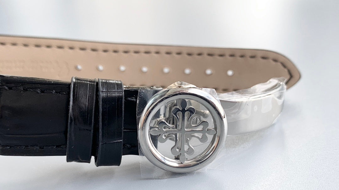 Black leather watch strap with round silver clasp and decorative emblem