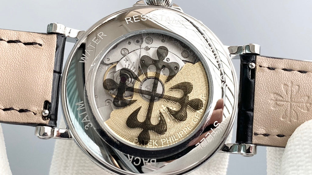 Transparent caseback view with floral-style movement and black leather strap