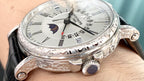 Luxury wristwatch side view with black leather strap, crown, and engraved bezel