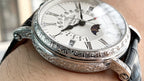 Luxury wristwatch angled on wrist, silver dial with Roman numerals and moonphase