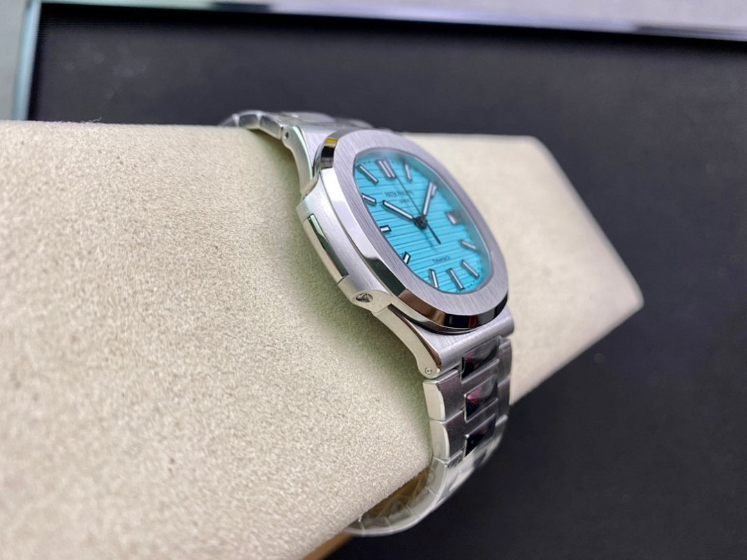 Stainless steel wristwatch with bright blue dial and metal bracelet, three-quarter view