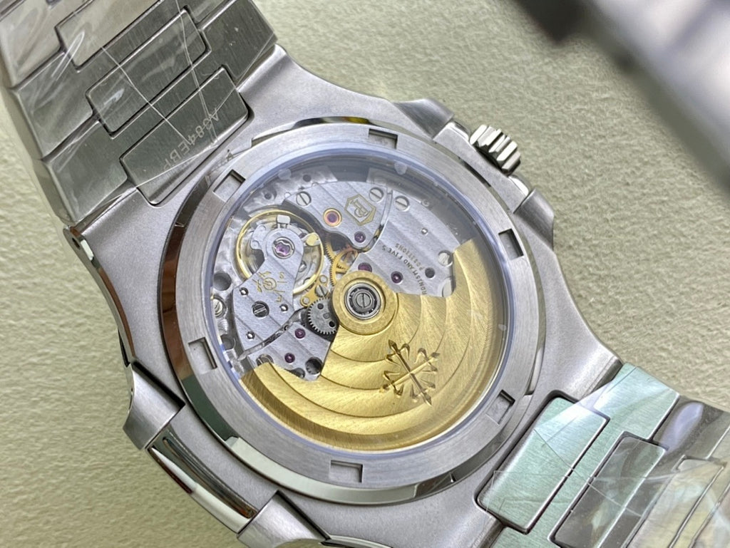 Patek Philippe watch open caseback with visible gold-toned movement and metal bracelet