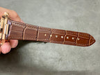 Brown leather watch strap with gold-tone buckle and stitched edge