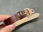Brown leather watch strap with gold deployant clasp and light beige keeper