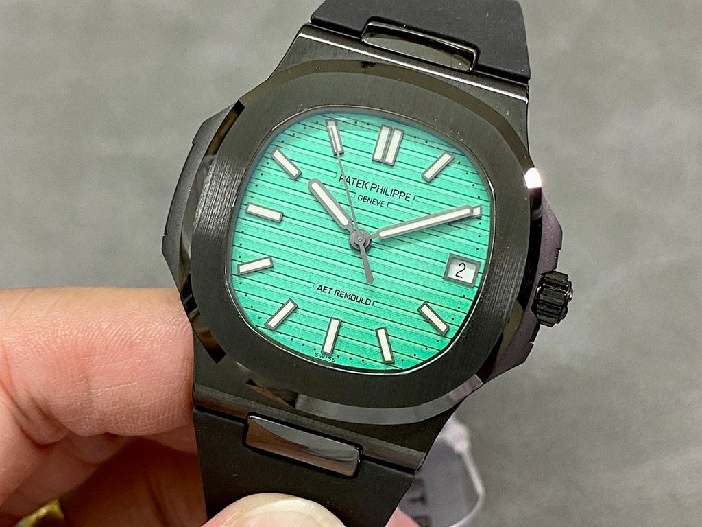 Black sport wristwatch with turquoise dial, baton markers, and date window at 3 o’clock