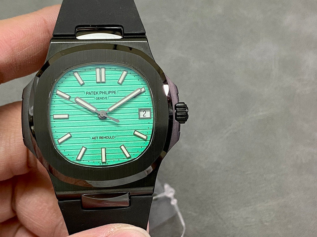 Black sport wristwatch with turquoise dial, baton markers, and date window at 3 o’clock