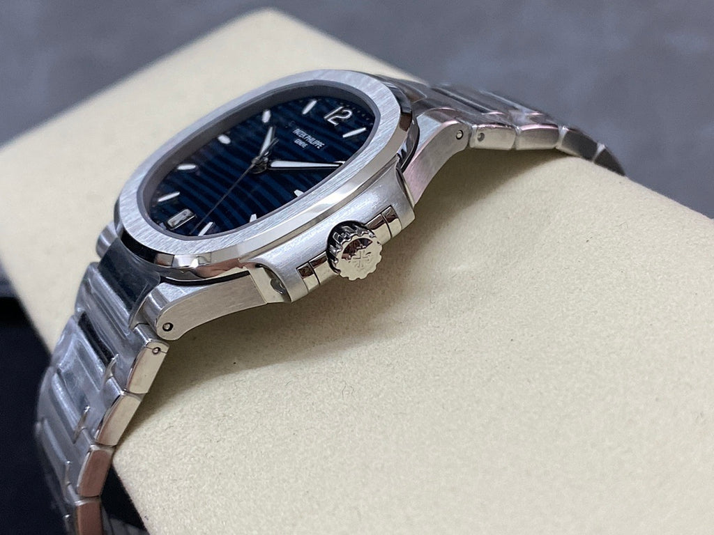 Steel wristwatch with blue dial, visible crown, and bracelet links on stand
