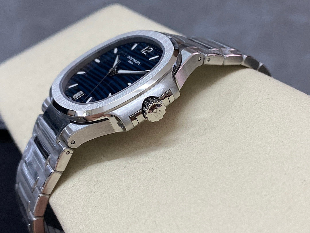 Steel wristwatch with blue dial, visible crown, and bracelet links on stand