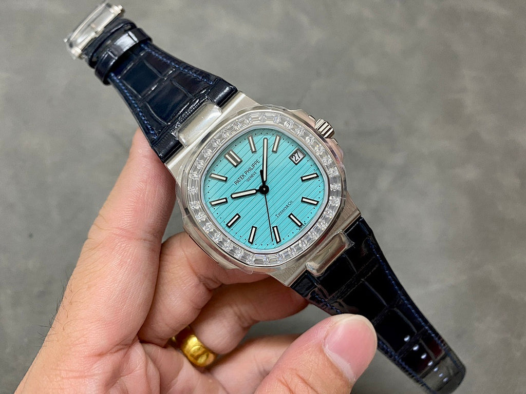Patek Philippe watch with teal dial, diamond bezel, and dark blue leather strap