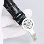 Patek Philippe watch black leather strap with round metal caseback badge, silver bezel