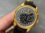 Gold wristwatch with black leather strap and black chronograph dial, visible subdials.