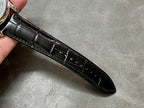 Black leather watch strap with stitched detailing and glossy buckle end