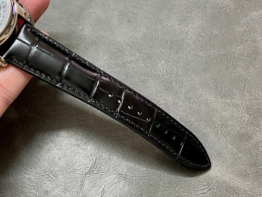 Black leather watch strap with stitched detailing and glossy buckle end