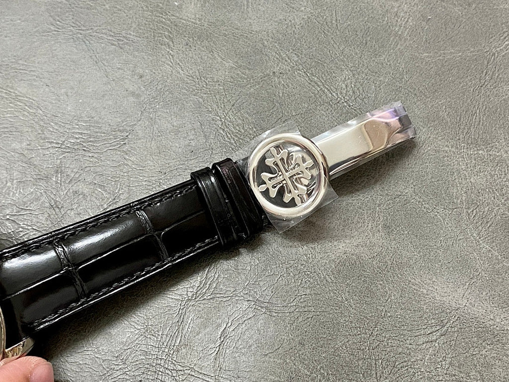 Black leather watch strap with silver-toned clasp and engraved emblem