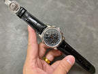 Wristwatch with black dial and silver case, black leather strap held in hand