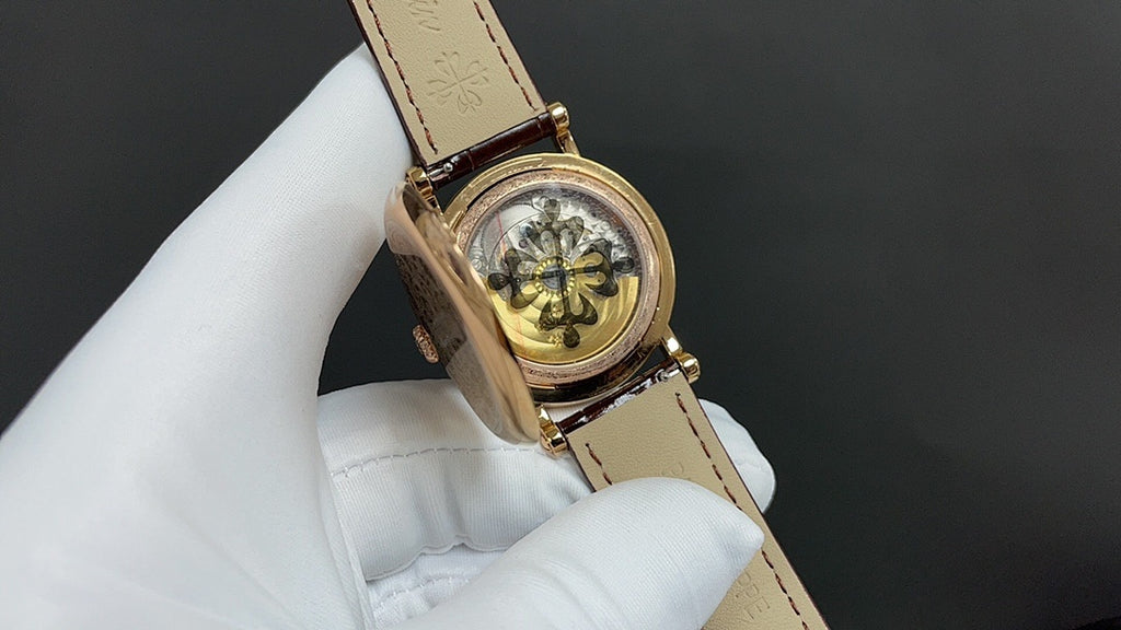 Gold wristwatch with brown leather strap, round engraved caseback and clasp