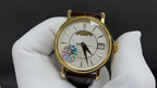 Patek Philippe wristwatch with gold bezel, white dial, brown leather strap
