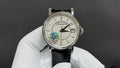 Patek Philippe wristwatch with white dial, black leather strap and silver bezel