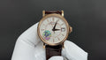 Gold-tone wristwatch with white dial, brown leather strap, three hands and subdials
