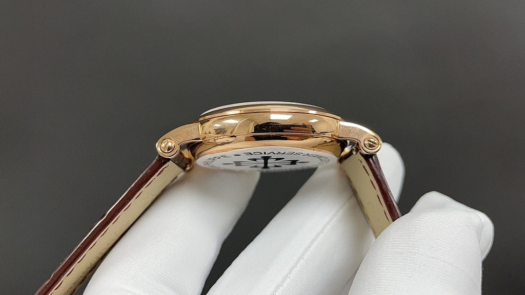 Gold-tone wristwatch case profile with crown and lugs, brown leather strap