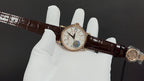 Gold-tone wristwatch with white dial on brown leather strap, clasp and crown visible