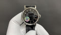 Patek Philippe wristwatch with black dial, silver case, and black leather strap