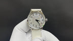 Wristwatch front view with silver dial, black hands, and light leather strap