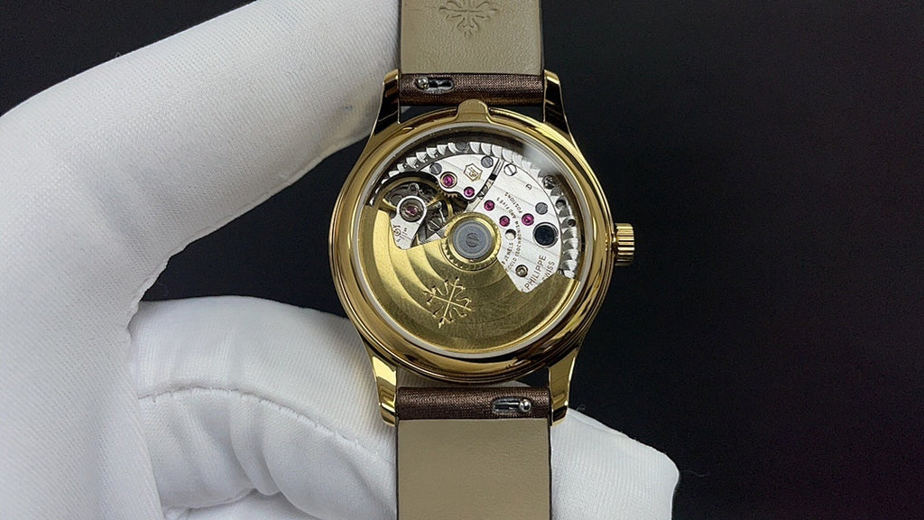 Patek Philippe watch open caseback view, showing mechanical movement and gold finish