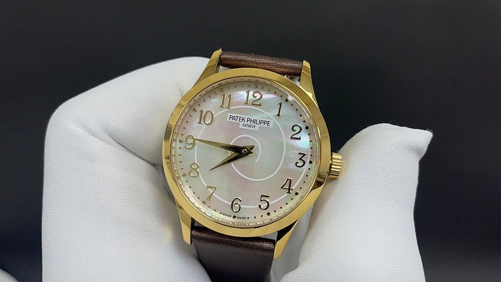 Gold watch with white dial and brown leather strap on white glove
