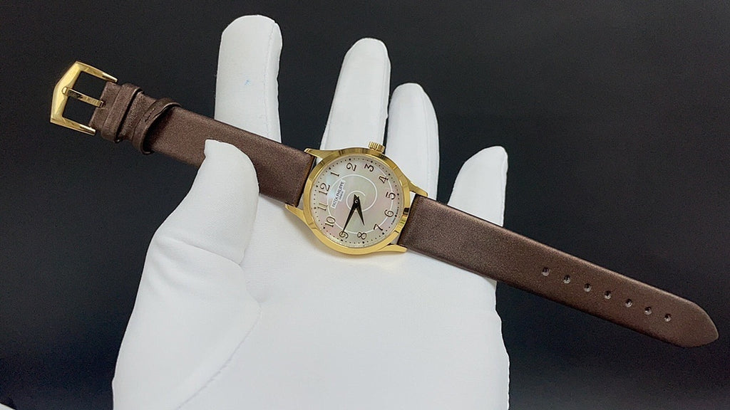 Brown leather strap watch on glove, gold buckle and dial visible