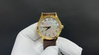 Gold Patek Philippe watch with white dial and brown leather strap