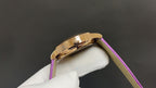 Gold wristwatch case with purple leather strap, side profile