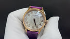 Gold wristwatch with purple leather strap, white dial with Arabic numerals