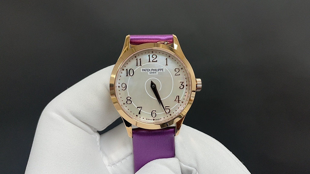 Gold wristwatch with purple leather strap, white dial centered with hour markers