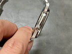 Patek Philippe watch clasp side view on metal bracelet, held between fingers