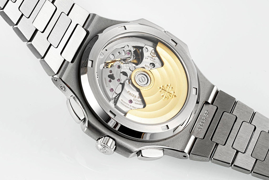 Stainless steel wristwatch open caseback showing mechanical movement and gold-toned parts