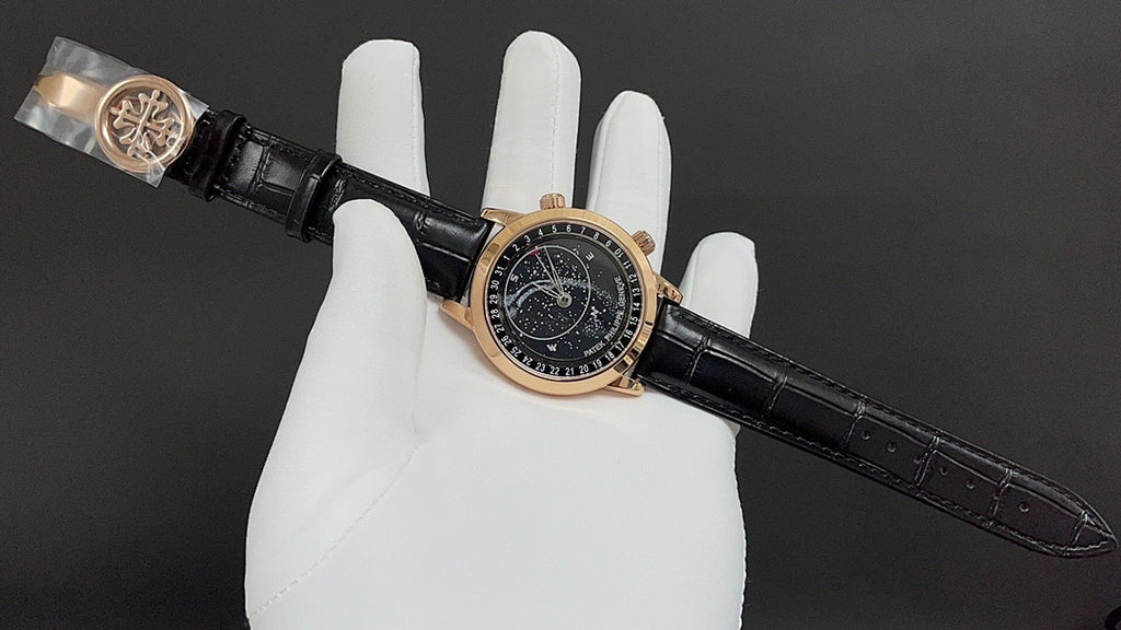 Luxury wristwatch on glove with black dial, gold-tone case, and black leather strap.