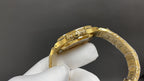 Gold-tone wristwatch bracelet with textured links and clasp, held on a glove